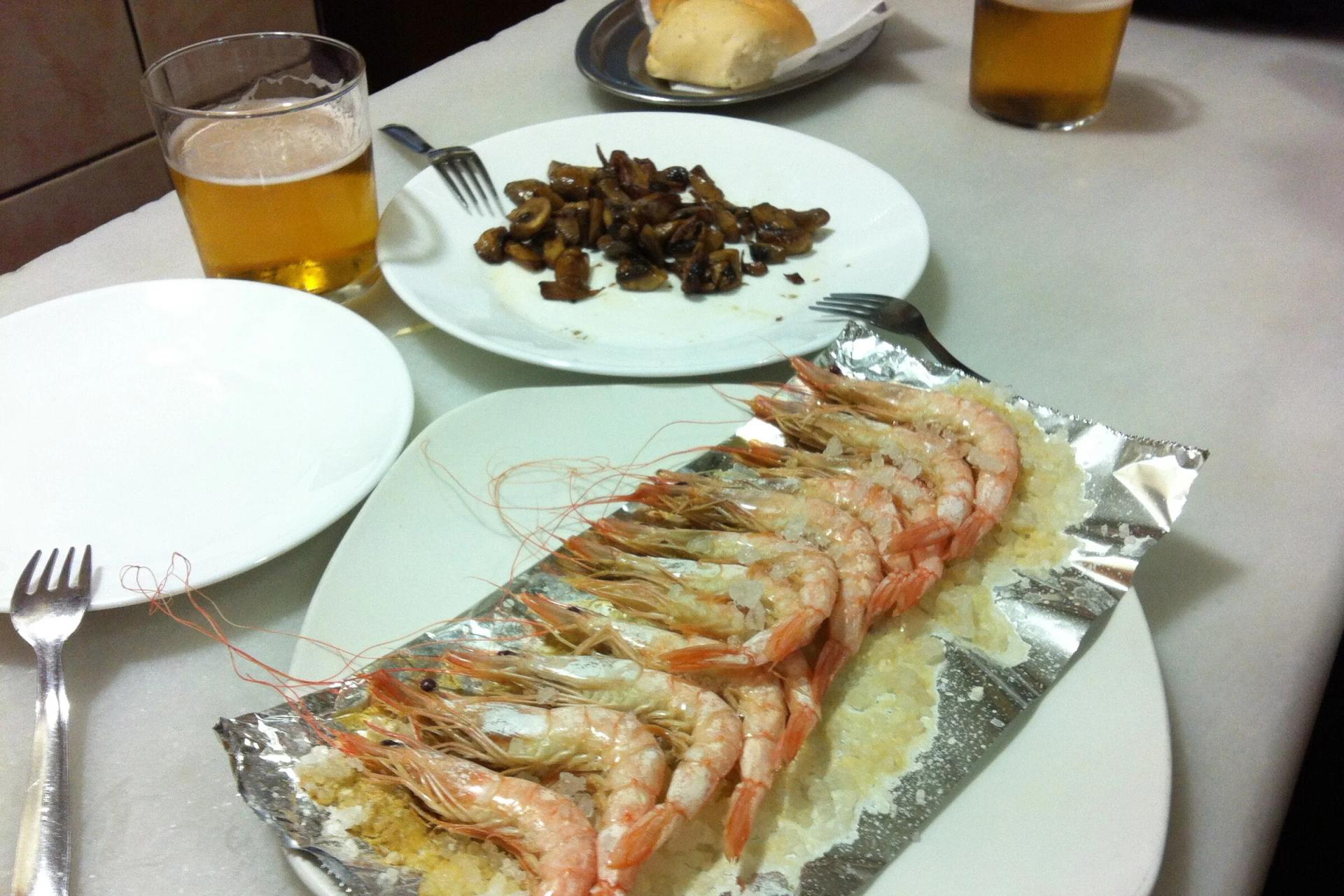 Gambas a la plancha sobre papel de aluminio junto a unas cañas en una mesa de Los Diamantes