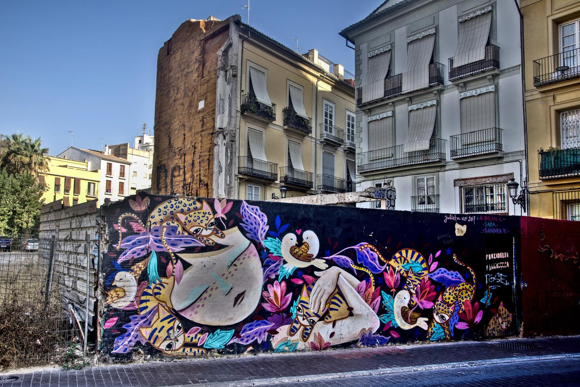 Mural de colores en la tapia de un solar del barrio del Carmen, delante de fachadas antiguas