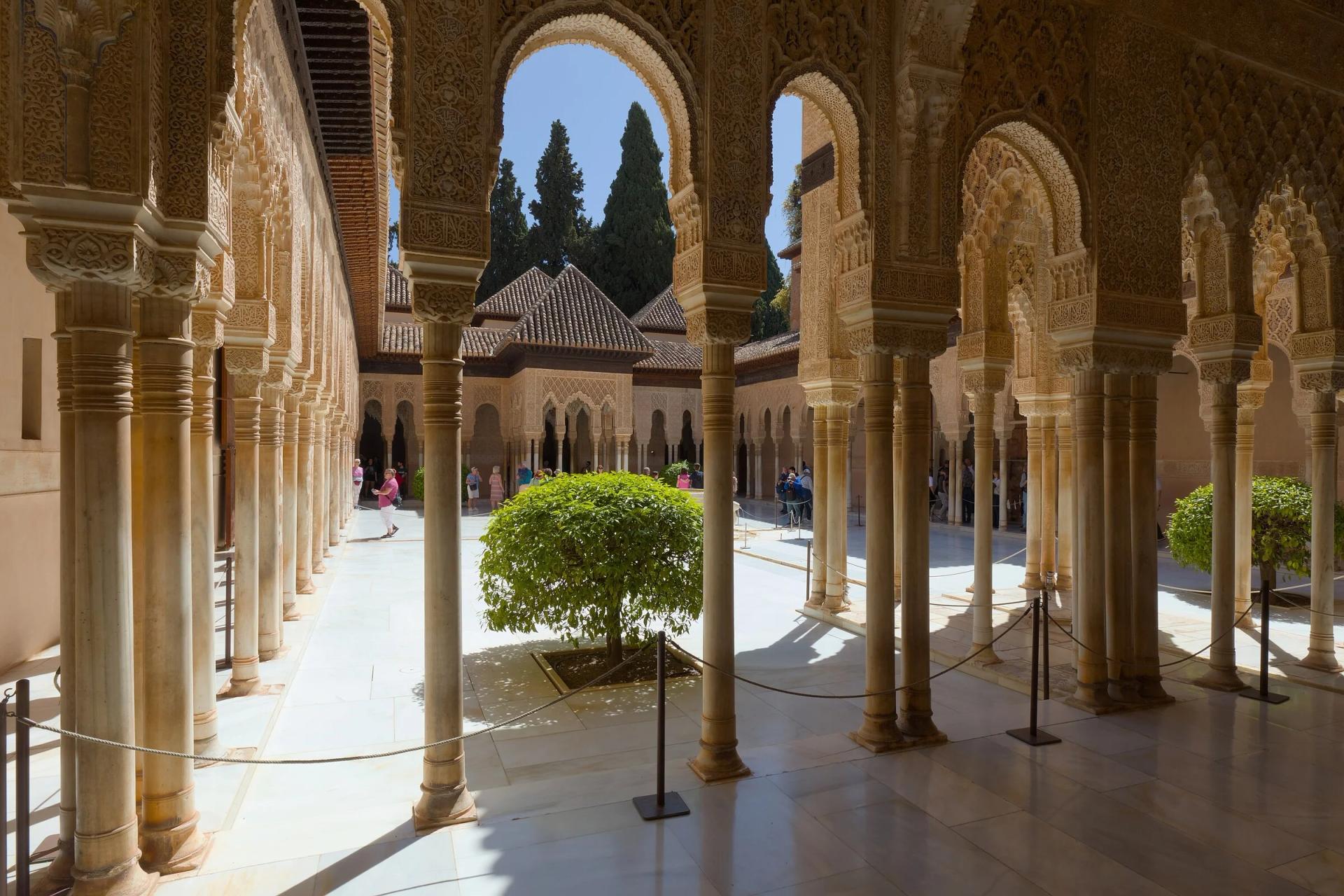 Patio de los Leones visto entre las columnas de mármol y los arcos de yesería de sus galerías