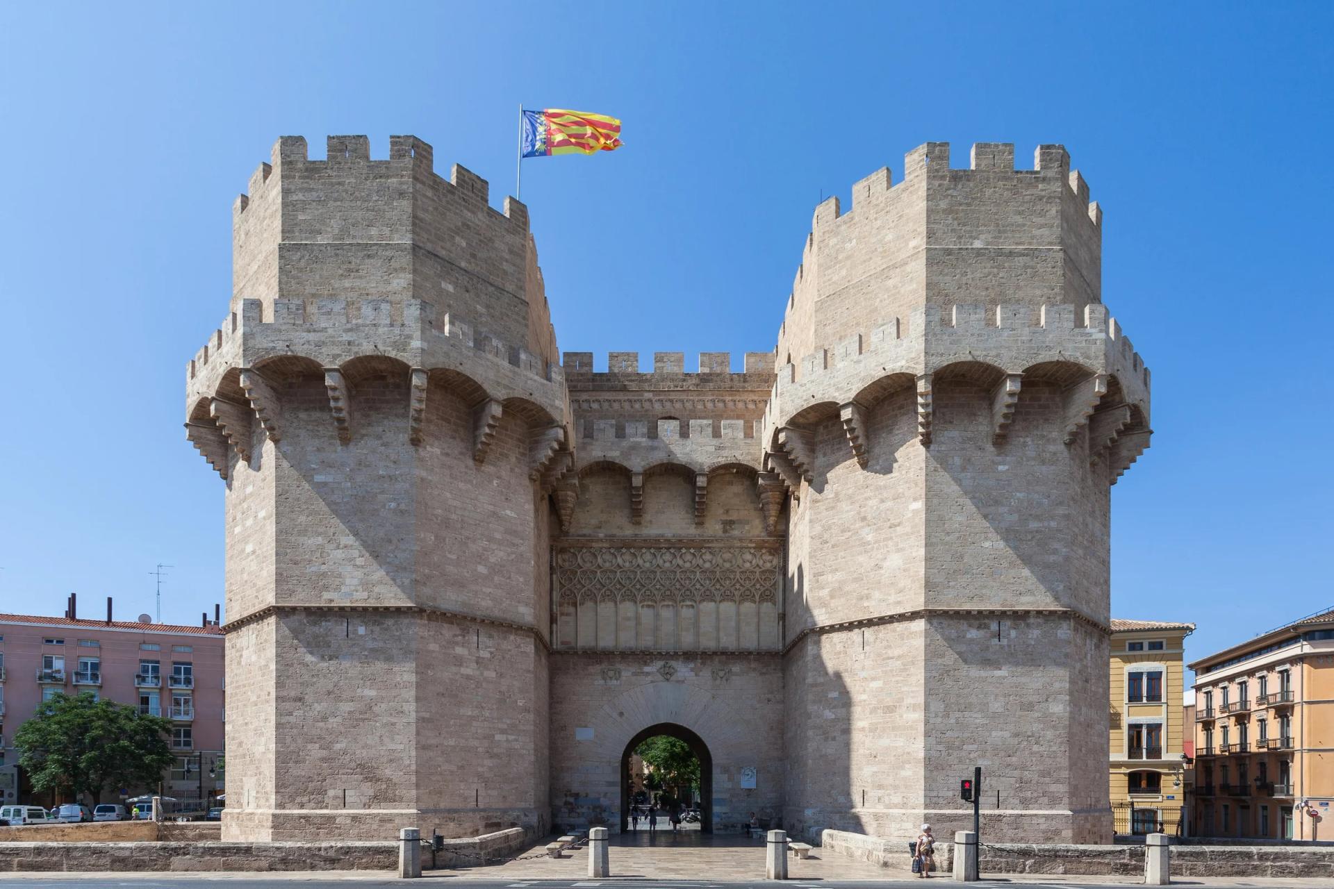 Las Torres de Serranos, dos torres almenadas a los lados del arco de entrada, contra el cielo azul