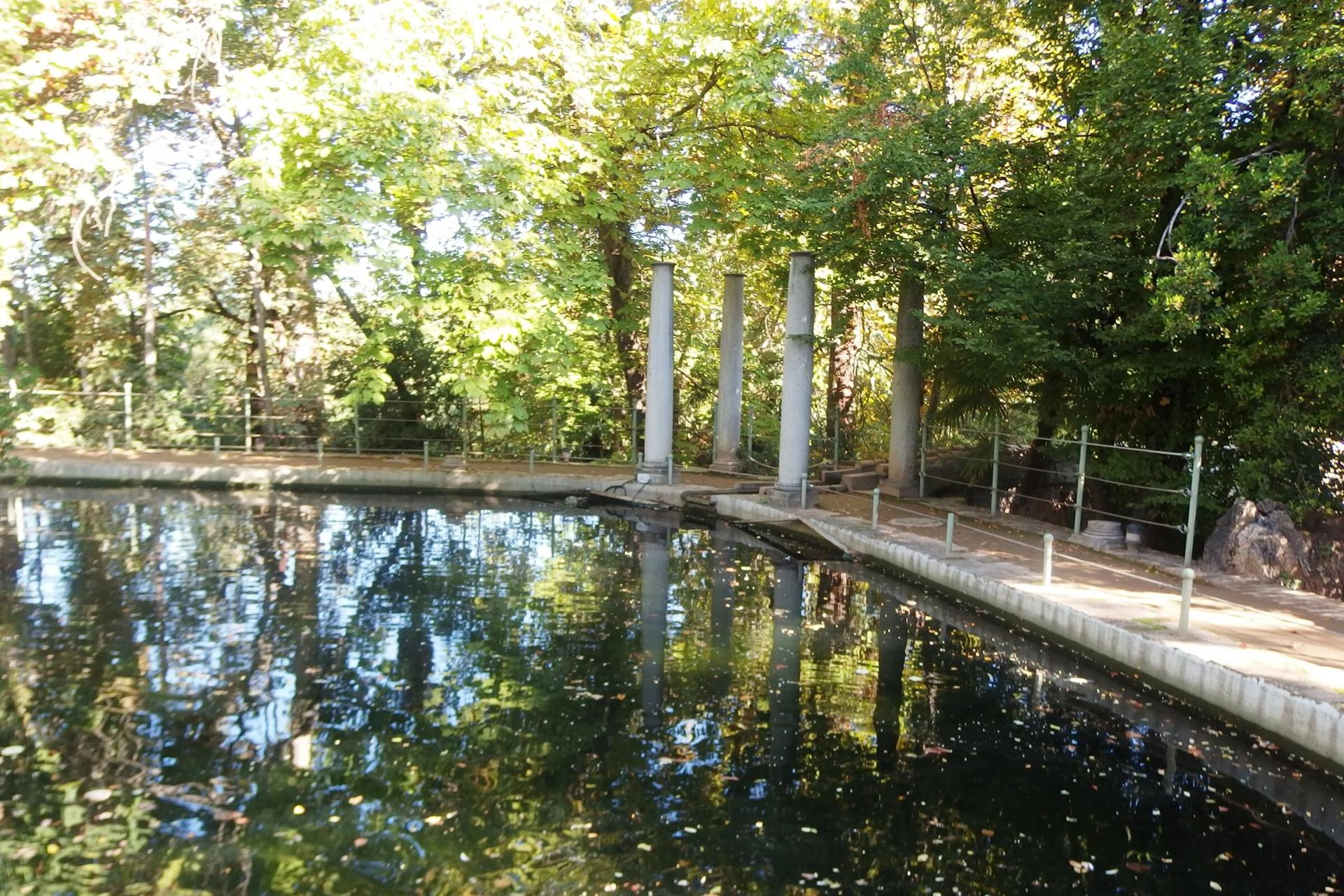 Estanque del Carmen de los Mártires rodeado de árboles, con columnas junto a la orilla