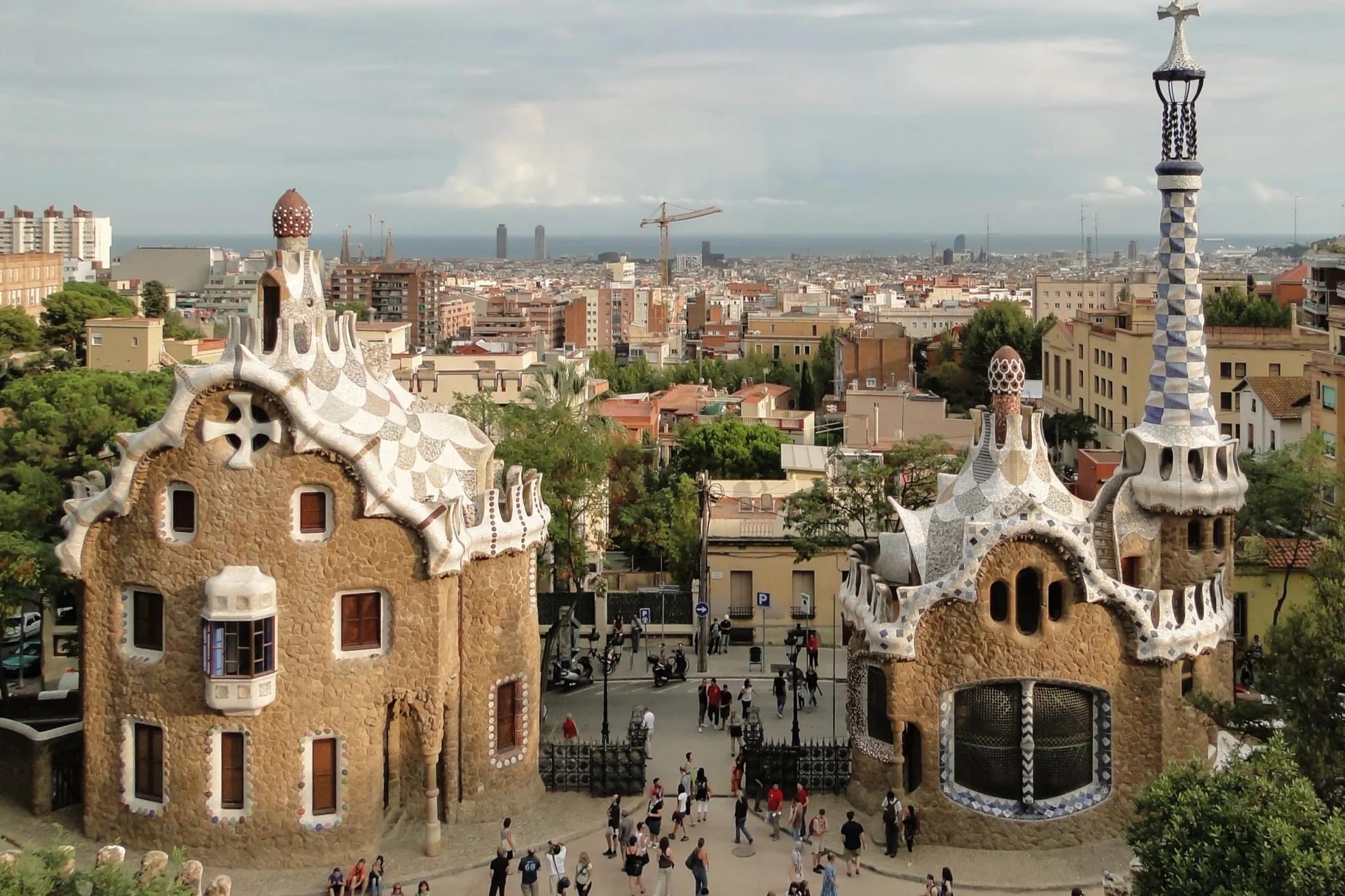 Los dos pabellones de la entrada del Park Güell, con sus tejados de trencadís, y la ciudad al fondo