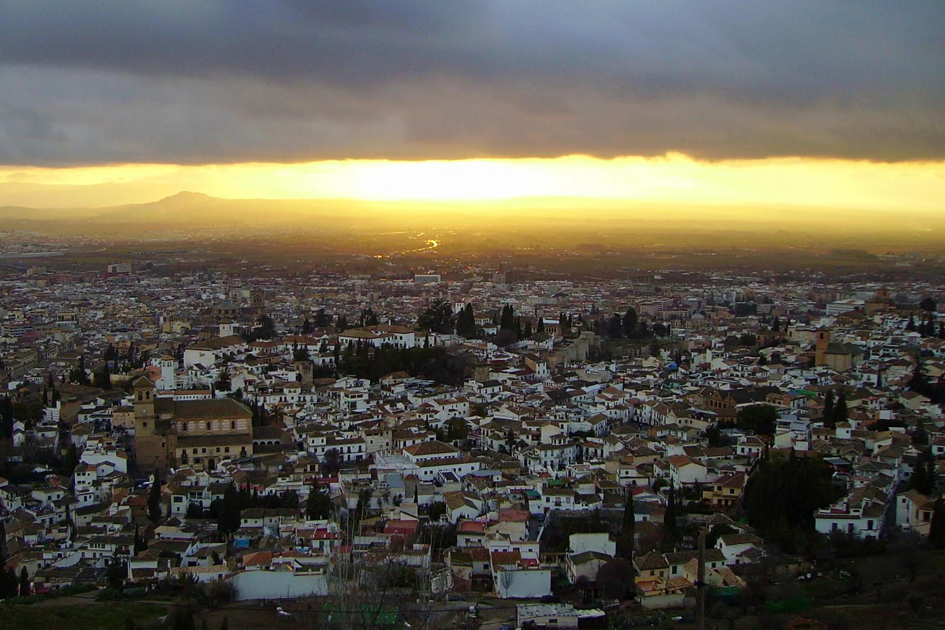 Granada entera al atardecer desde el mirador de San Miguel Alto, con la vega y el cielo encendido al fondo