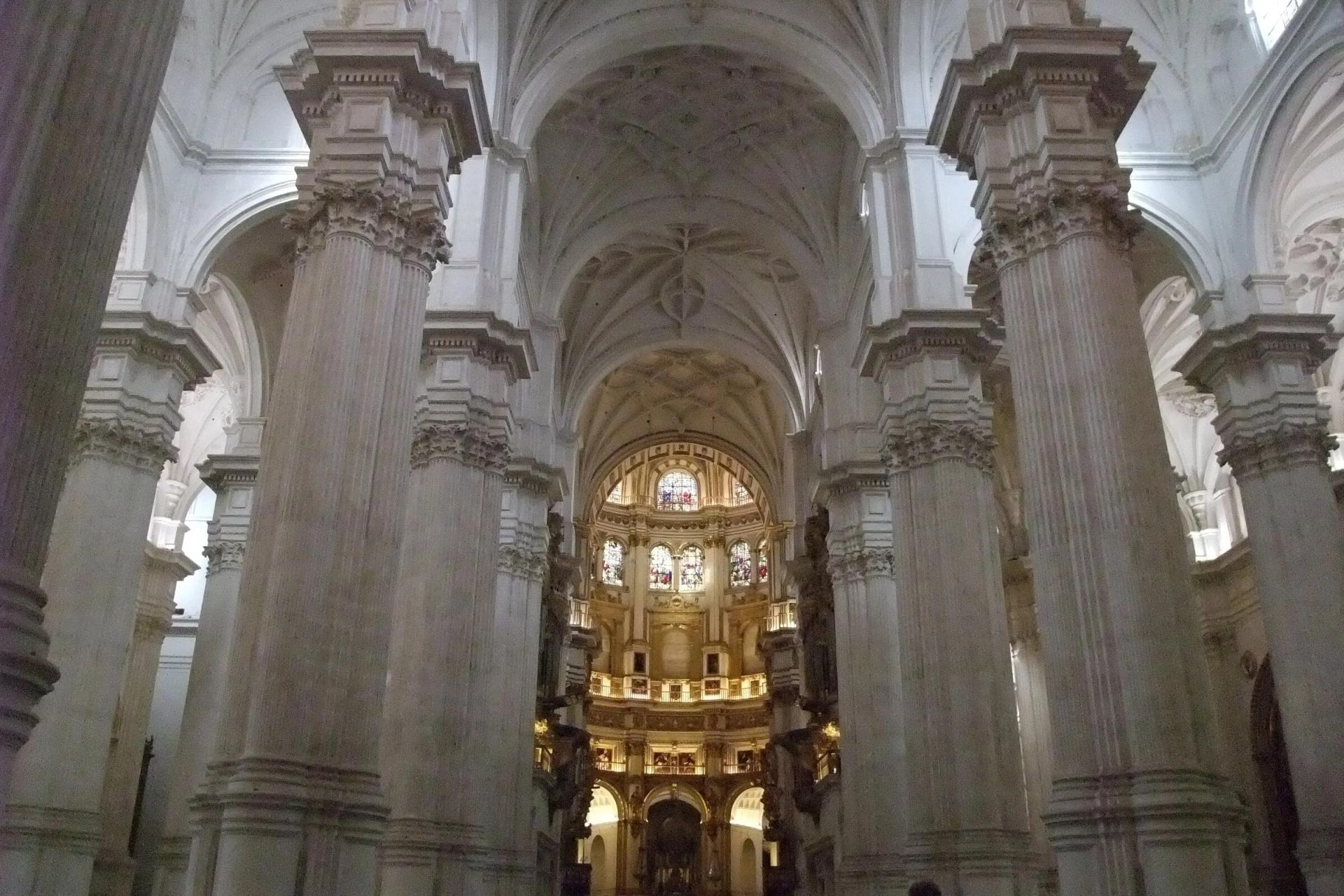 Nave mayor de la Catedral de Granada, con sus grandes pilares blancos y la capilla mayor dorada al fondo