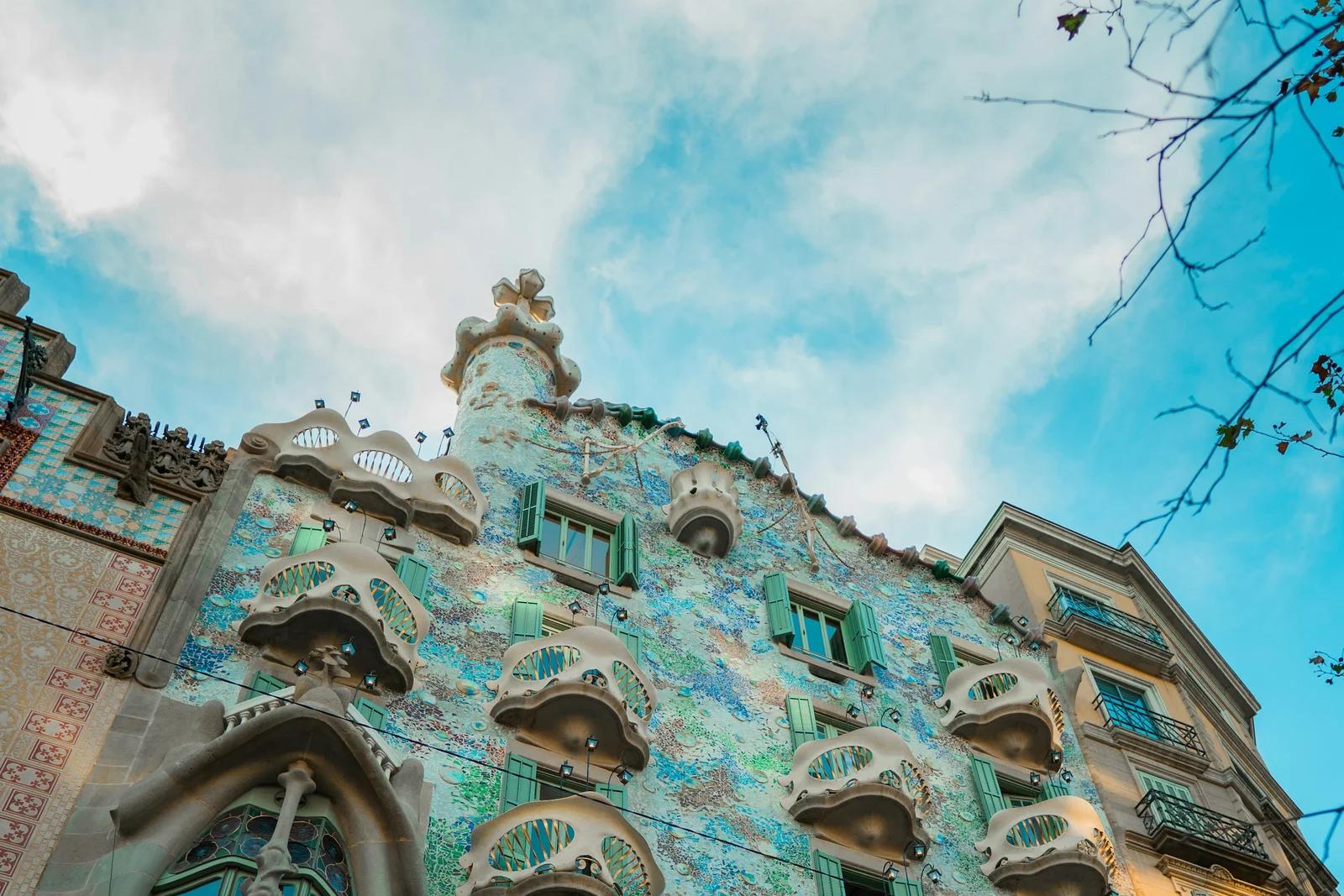 Fachada de la Casa Batlló vista desde abajo, con sus balcones en forma de máscara y el mosaico azulado