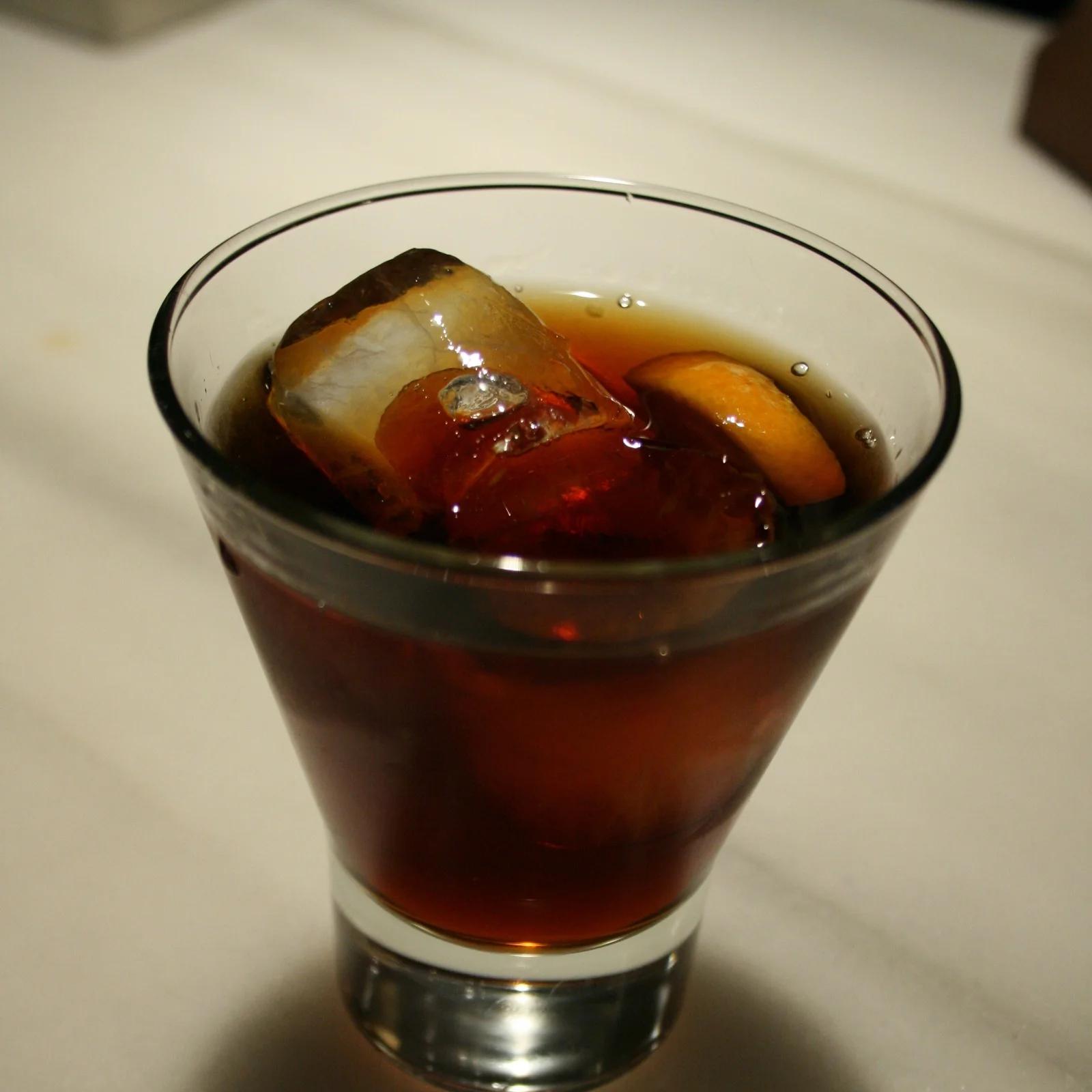 Vaso de vermut rojo con hielo y una rodaja de naranja