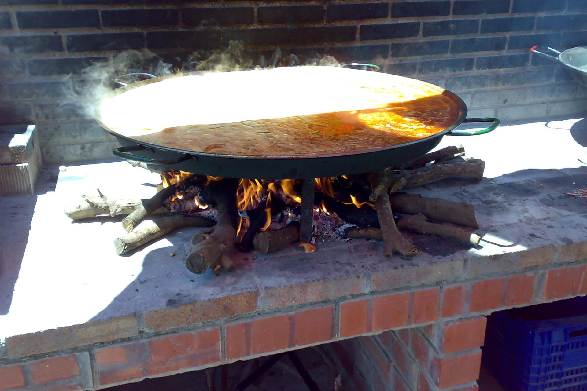 Una paella haciéndose a la leña en Valencia, el método por el que se conoce a Casa Carmela