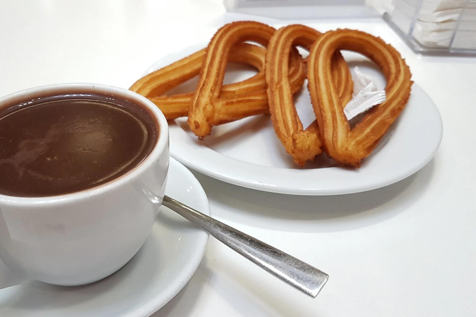 Taza de chocolate caliente con un plato de churros