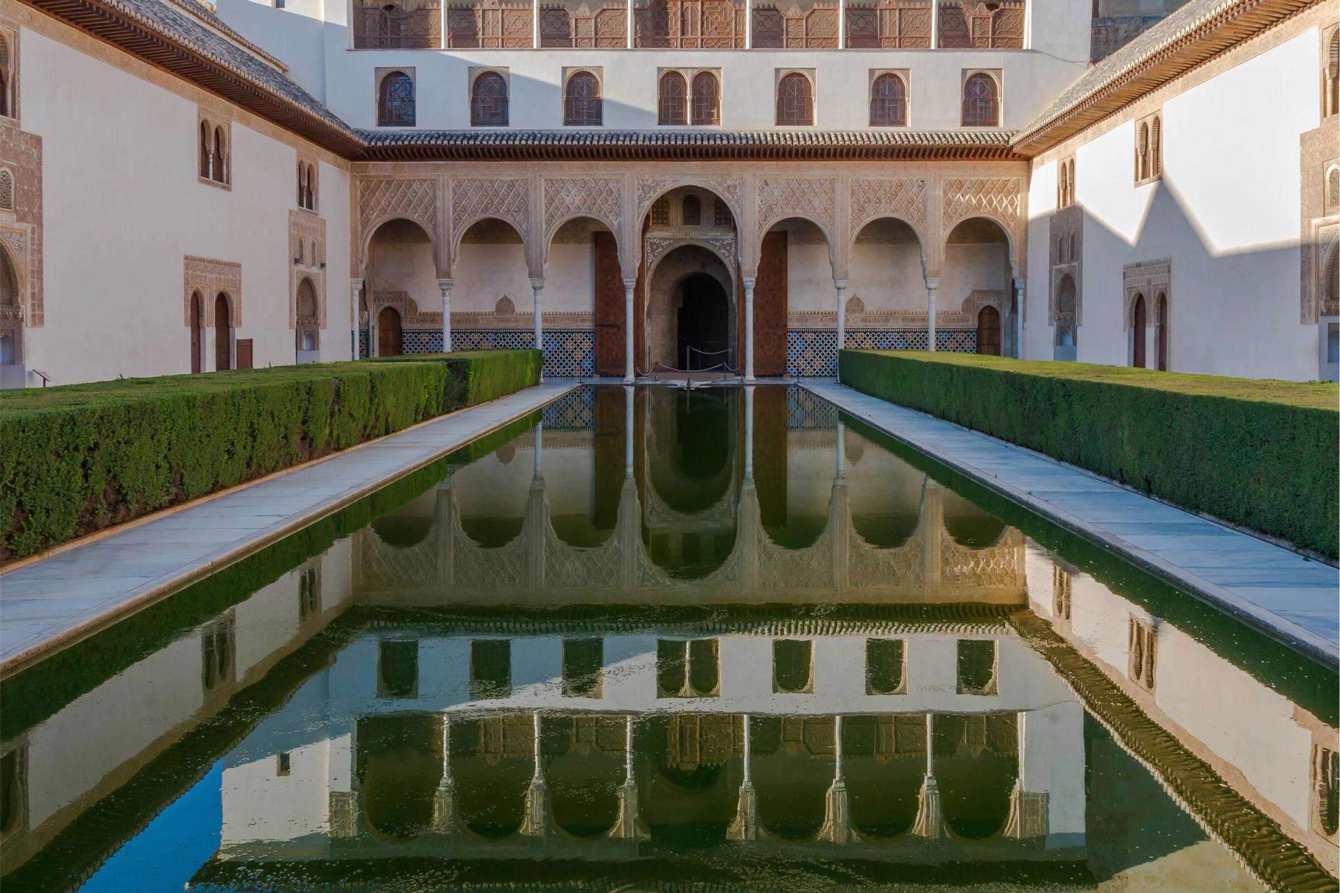Patio de los Arrayanes de la Alhambra, con la fachada de arcos reflejada en la alberca entre setos de arrayán