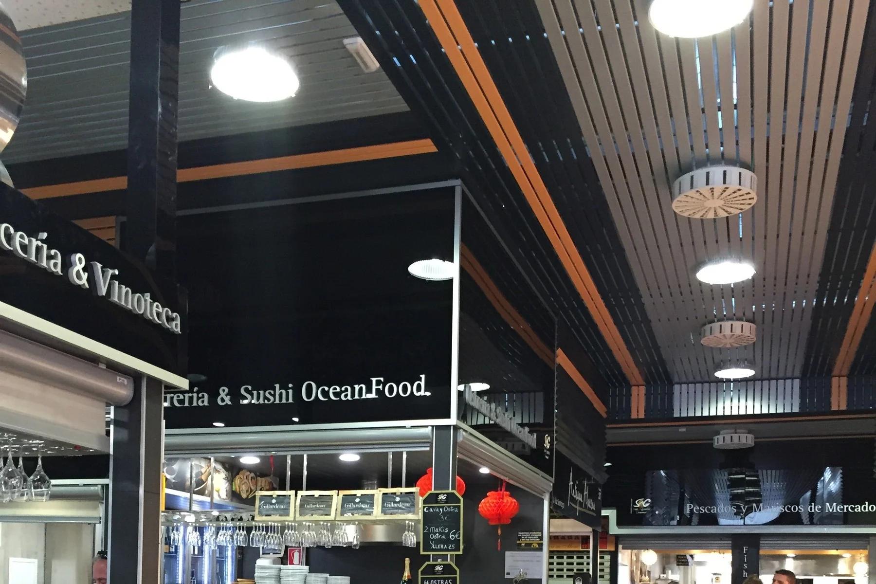 Interior del Mercado de San Agustín, con barras, taburetes altos y puestos bajo un techo de lamas