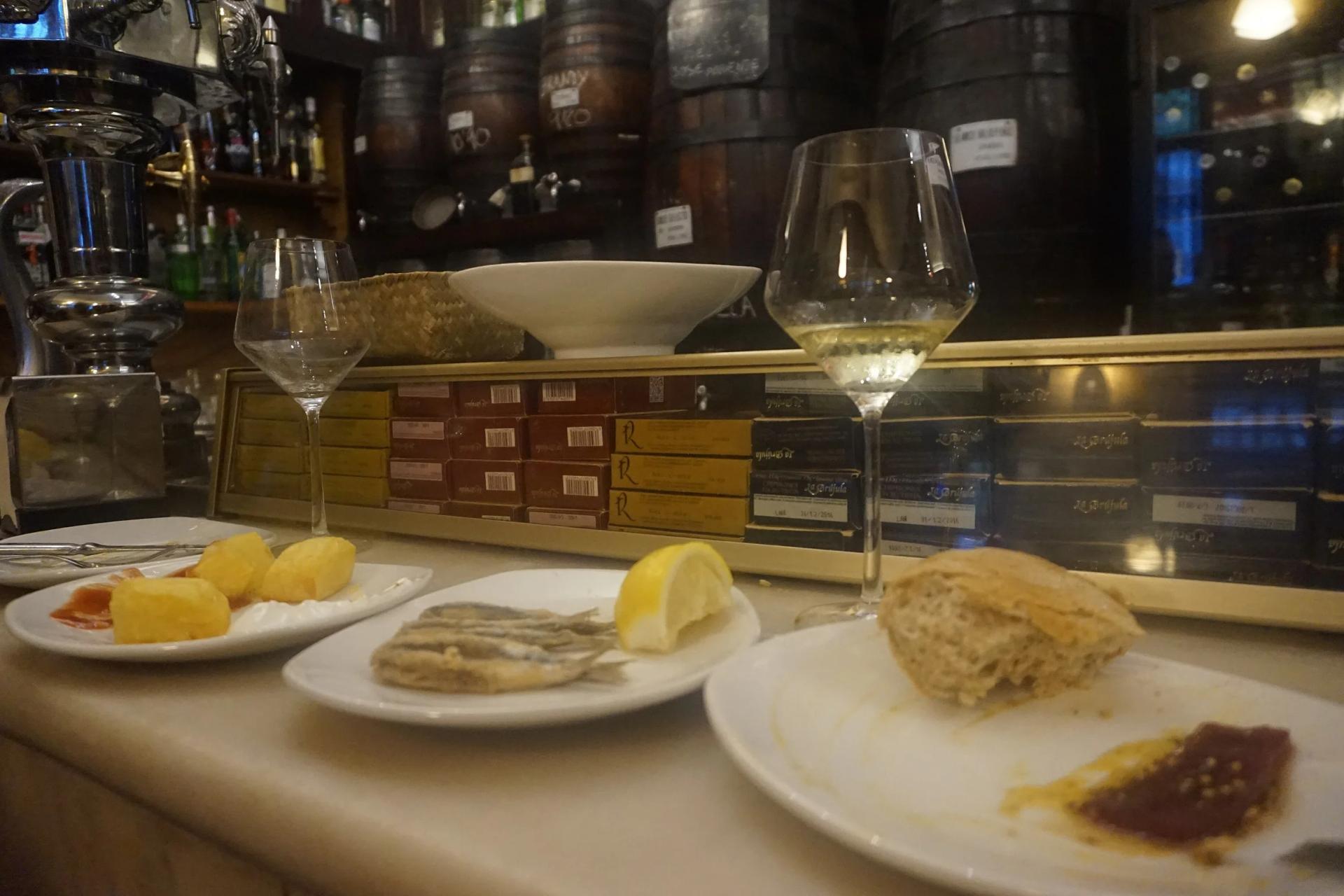 Barra de Casa Montaña con tapas, copas de vino y toneles al fondo