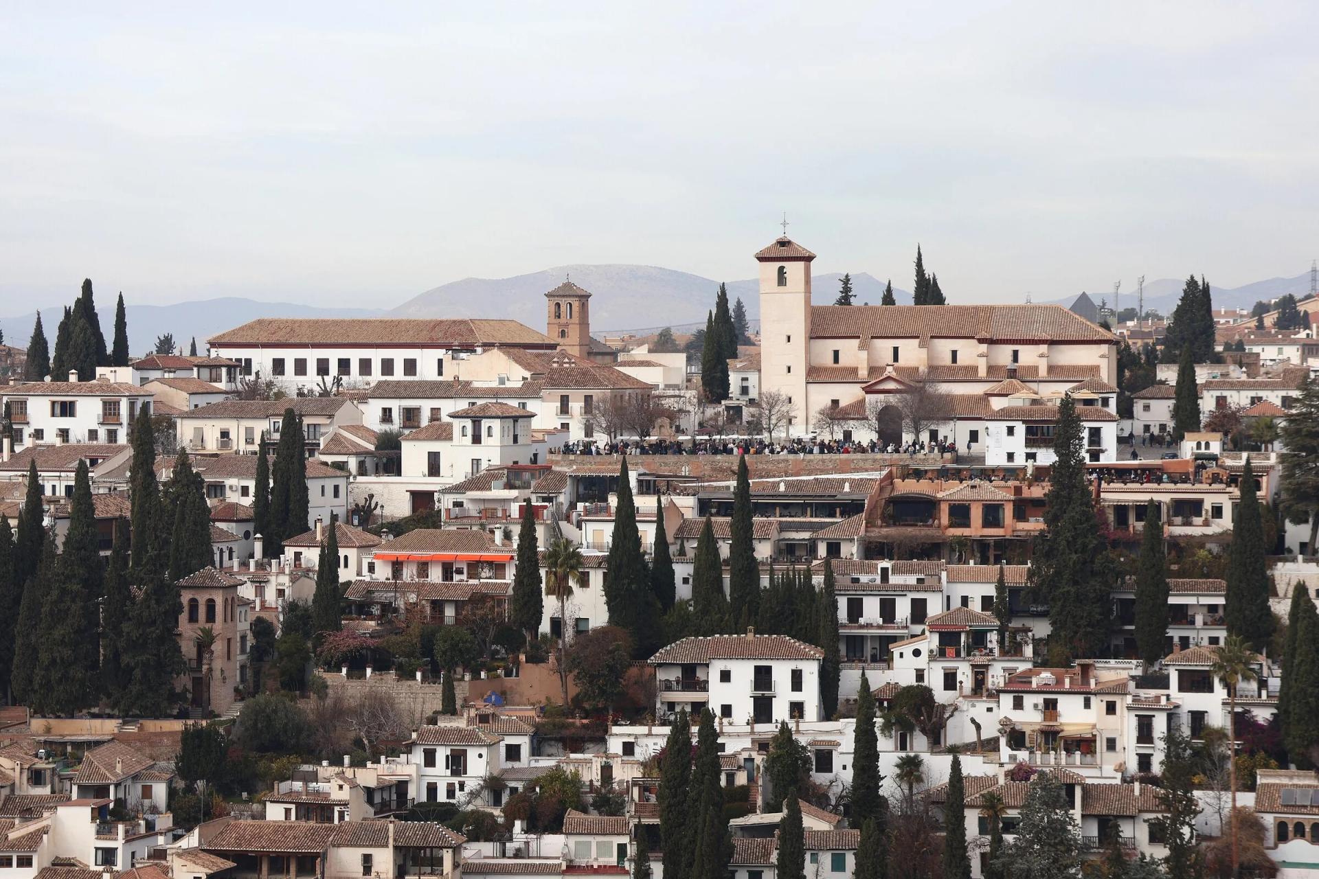 Casas blancas y cipreses del Albaicín en la ladera, con la iglesia de San Nicolás en lo alto, vistos desde la Alhambra