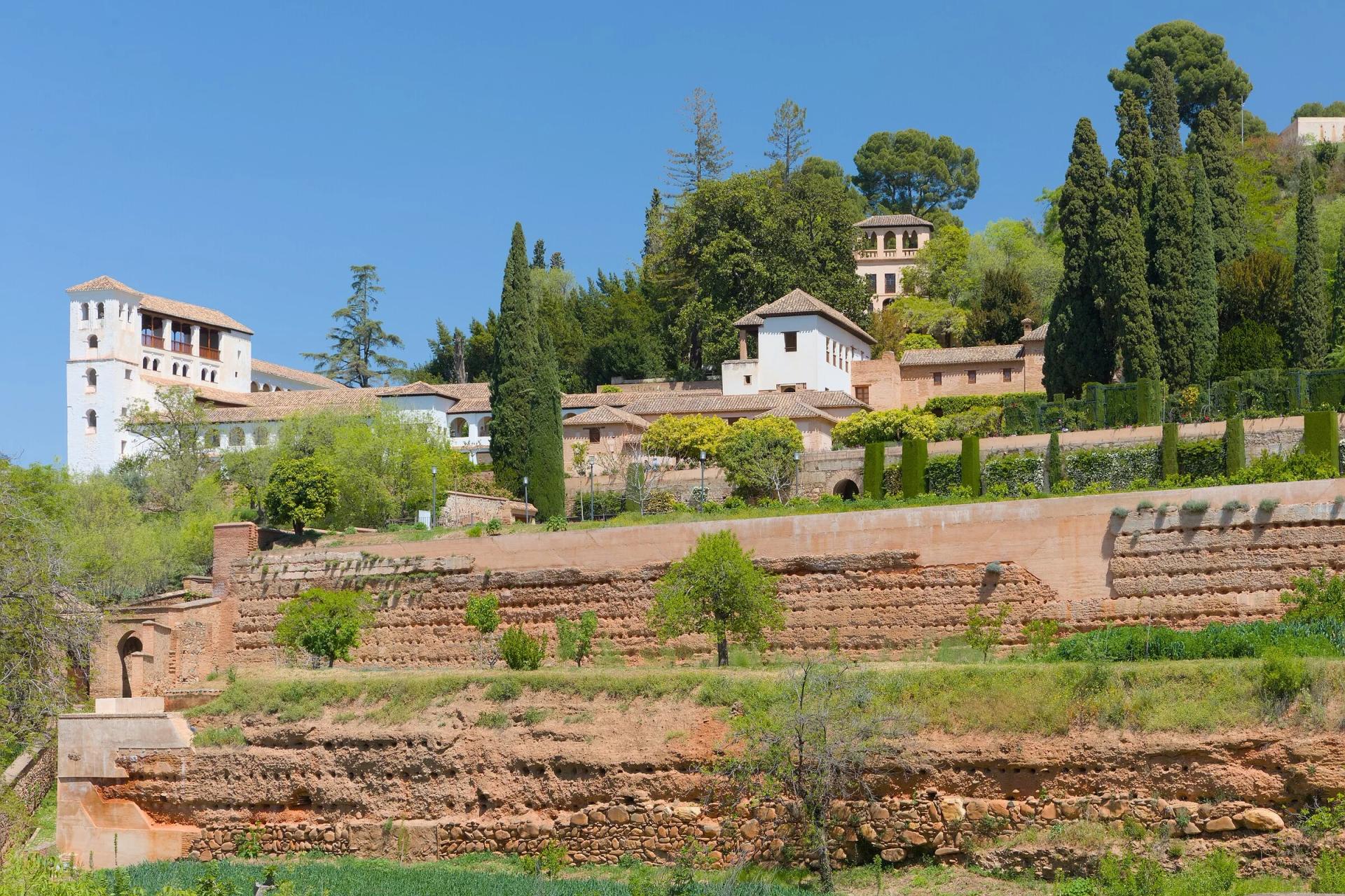 El Generalife y sus terrazas ajardinadas vistos desde los jardines del Partal, bajo un cielo azul