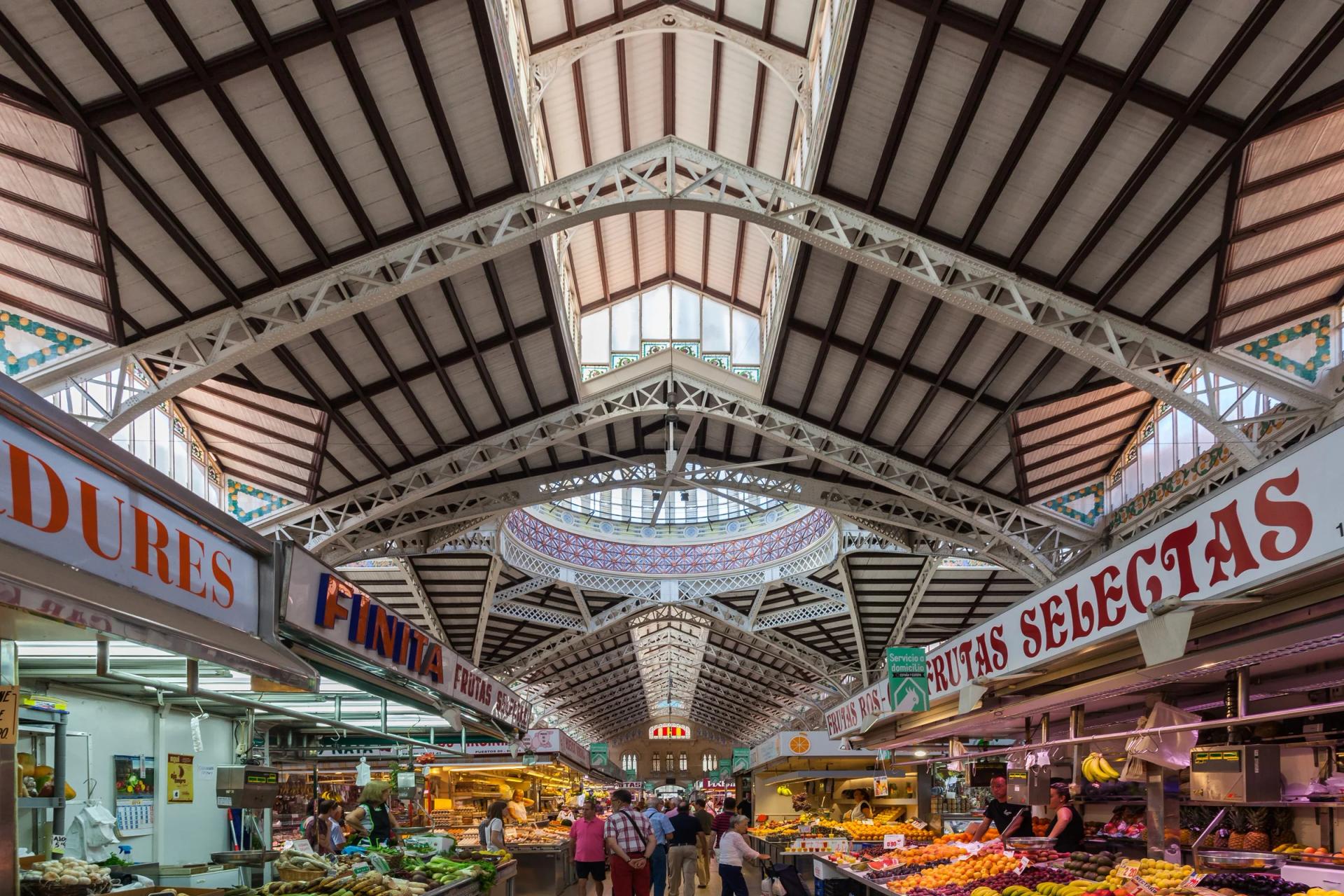 Interior del Mercado Central, con puestos de fruta y verdura bajo la cúpula y la estructura de hierro