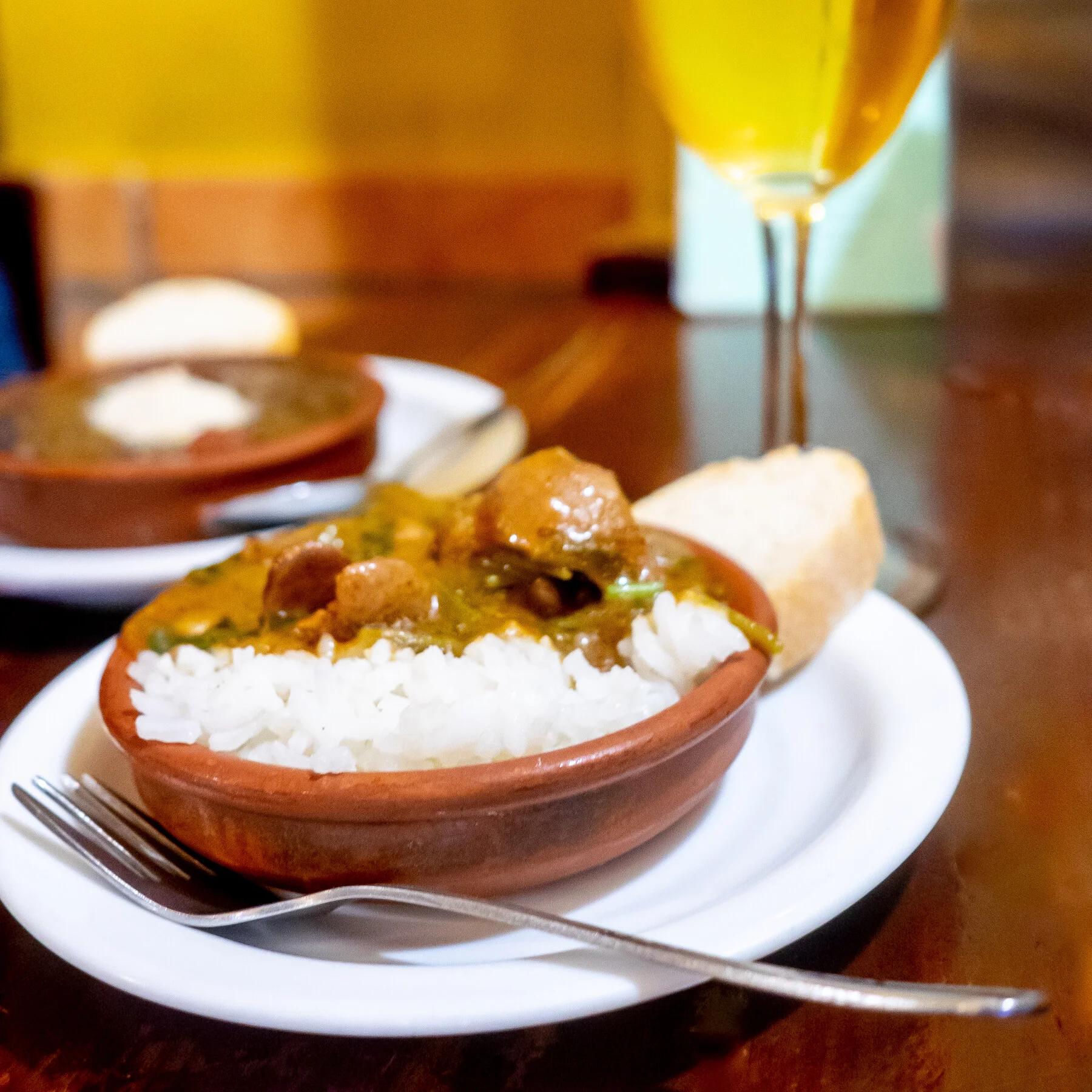 Cazuelita de arroz con guiso, pan y una copa de cerveza en la mesa de un bar de Granada