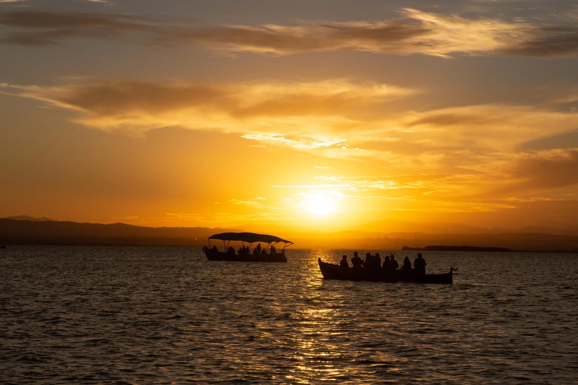 Barcas sobre la Albufera al atardecer, recortadas contra el sol que se pone