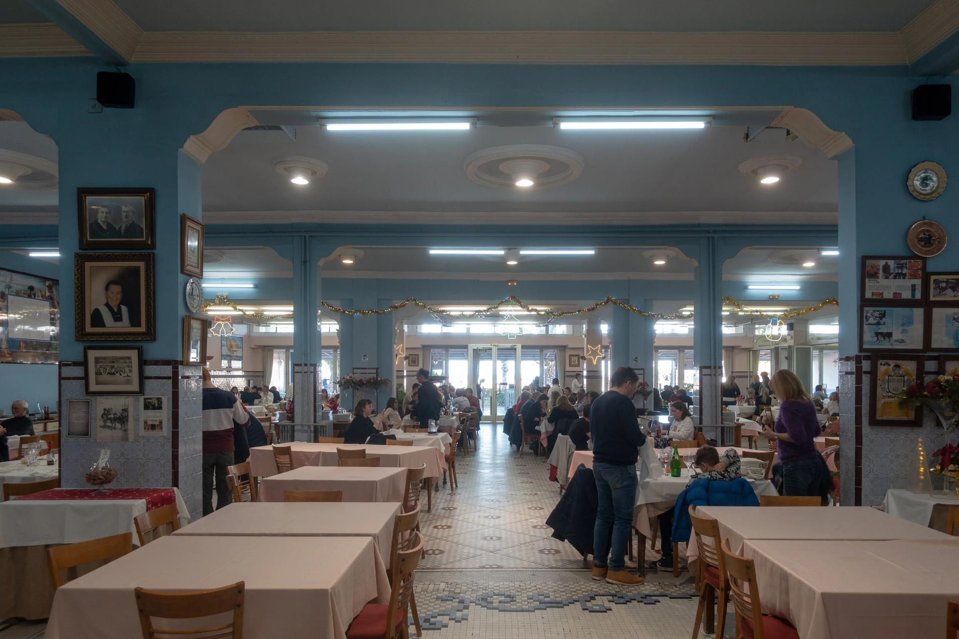Comedor de La Pepica, con paredes azules, fotos enmarcadas y suelo de mosaico